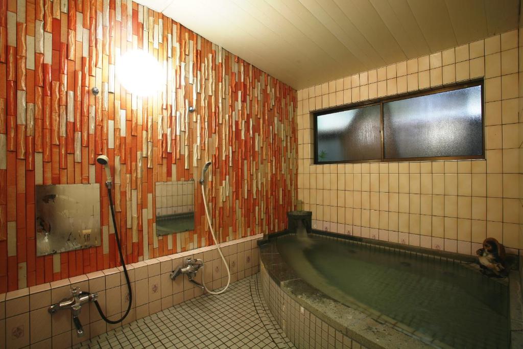 La salle de bains est pourvue d'une baignoire, d'une fenêtre et d'une baignoire. dans l'établissement Tabinoyado Kiunsoh, à Ōda