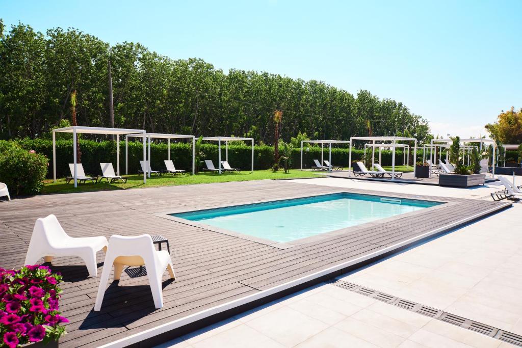 - une piscine avec des chaises blanches et une table dans l'établissement Hotel Quadrifoglio, à Pontecagnano 76 autres photos