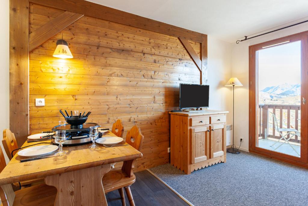 Cette chambre est dotée d'un mur en bois, d'une table et d'une télévision. dans l'établissement Les Alpages du Corbier A003, au Corbier
