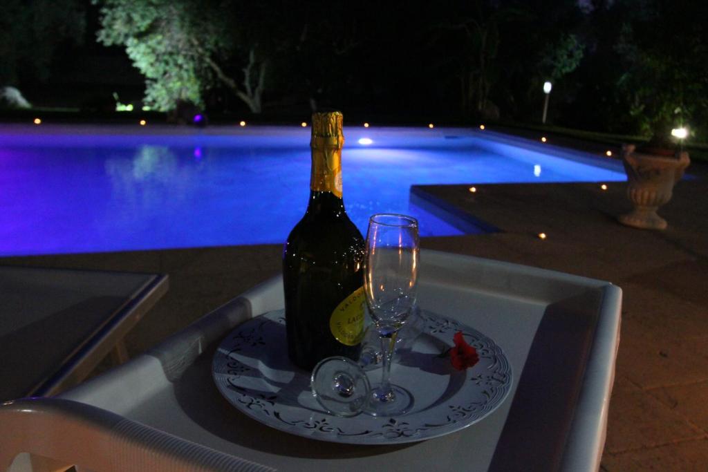 une bouteille de vin sur une assiette avec un verre dans l'établissement Villa Luisa villa con piscina e Vasca Idromassaggio vicino Otranto, à Carpignano Salentino
