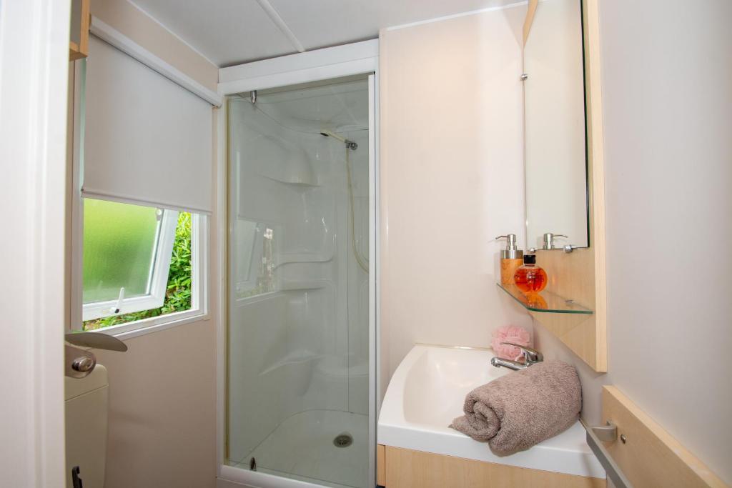 une salle de bain avec une douche en verre et un lavabo dans l'établissement Camping de la Baie, à Cavalaire-sur-Mer