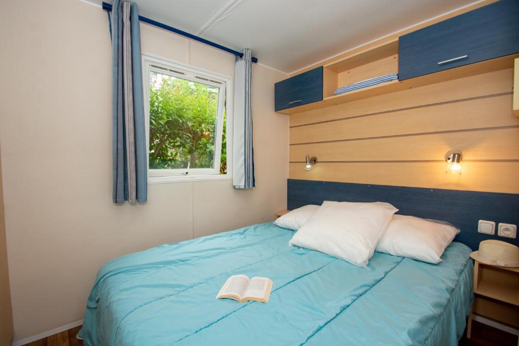 une chambre avec un lit avec deux livres dessus dans l'établissement Camping de la Baie, à Cavalaire-sur-Mer
