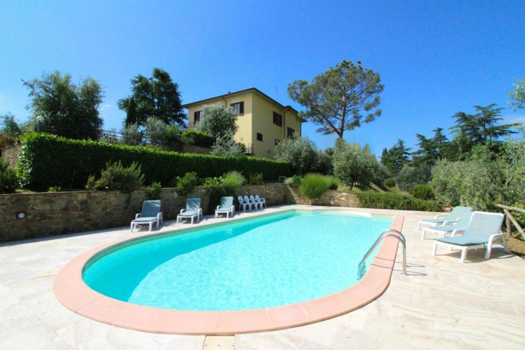 une piscine avec des chaises et une maison en arrière-plan dans l'établissement Il Poggiolo, à Monte San Savino