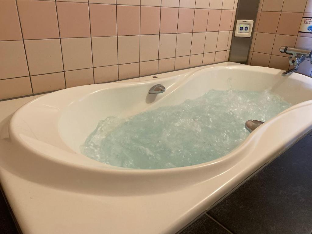 La salle de bains est pourvue d'une baignoire remplie d'eau. dans l'établissement プレゼントホテル チャペルガーデン 可児 ｰ大人専用ｰ, à Kani
