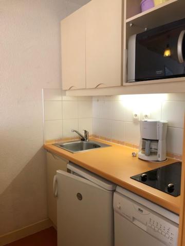une petite cuisine avec un évier et un micro-ondes dans l'établissement Pied des pistes, lumineux 4p, parking couvert, à La Mongie