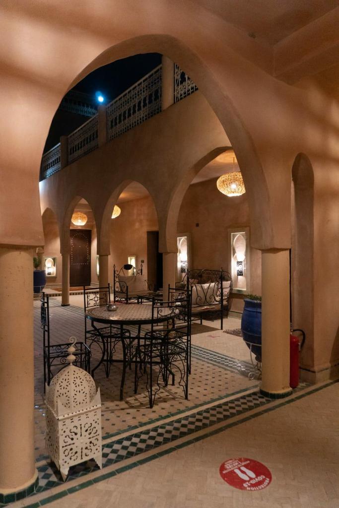 un patio avec tables et chaises dans un bâtiment dans l'établissement Maison Hassan Merzouga, à Merzouga