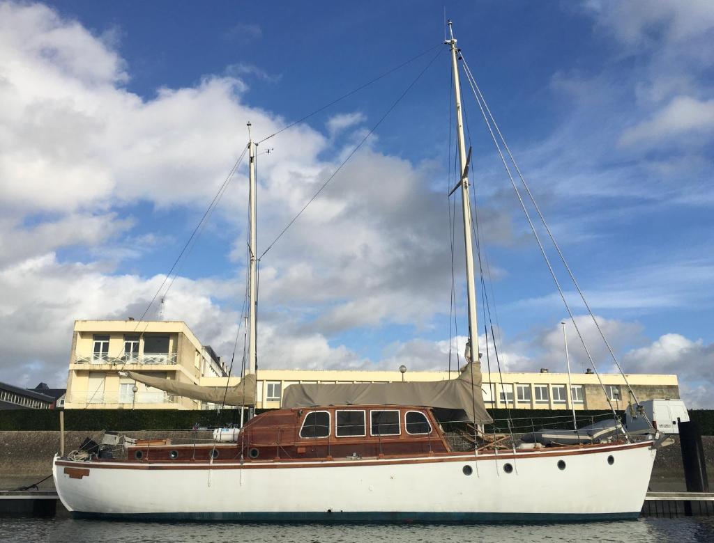 un bateau assis à l'eau devant un bâtiment dans l'établissement Port Deauville Yacht vintage, à Deauville