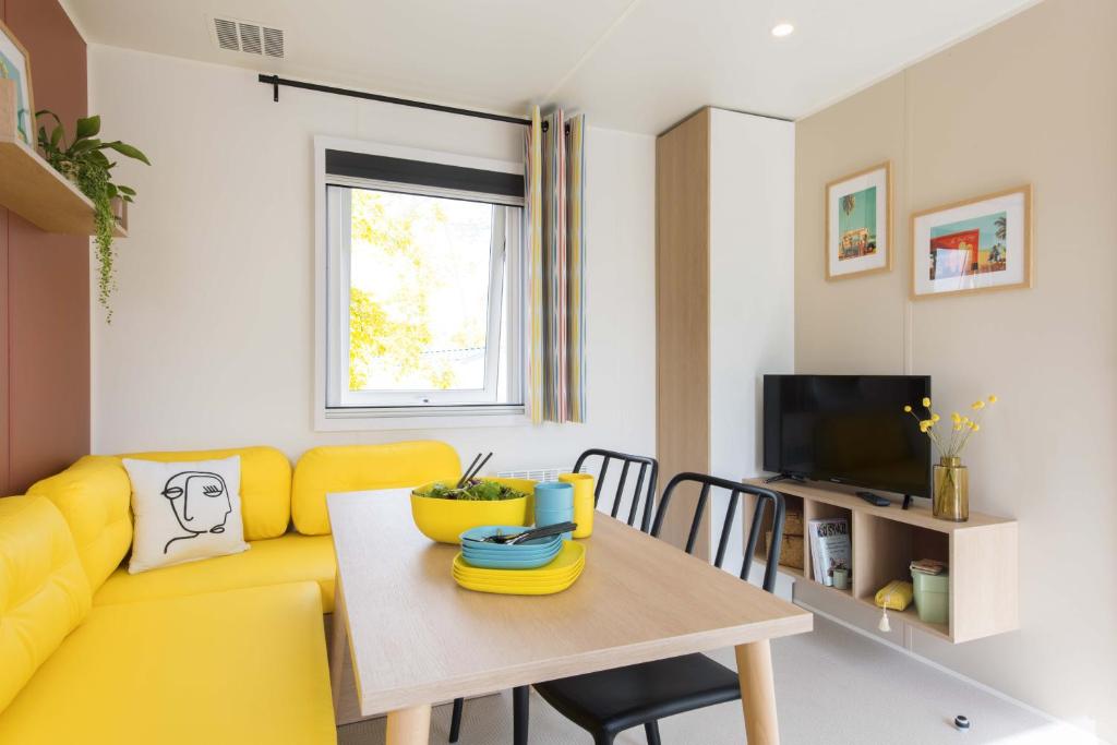 un salon avec un canapé jaune et une table dans l'établissement Camping Le Picard, à Tournières