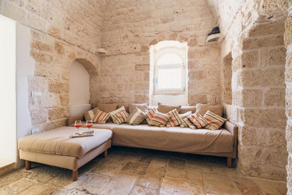 - un salon avec un canapé au mur en pierre dans l'établissement HelloApulia - Trulli tra Pietre Full, à Ceglie Messapica