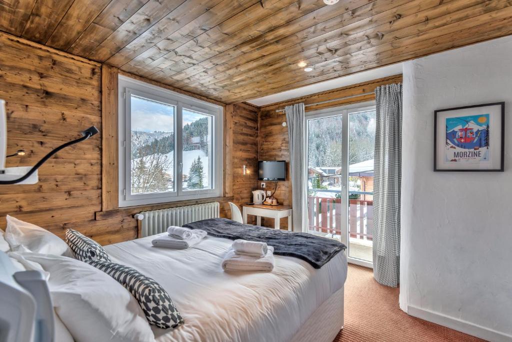 une chambre avec un lit dans une pièce aux murs en bois dans l'établissement Hôtel La Chaumière, à Morzine