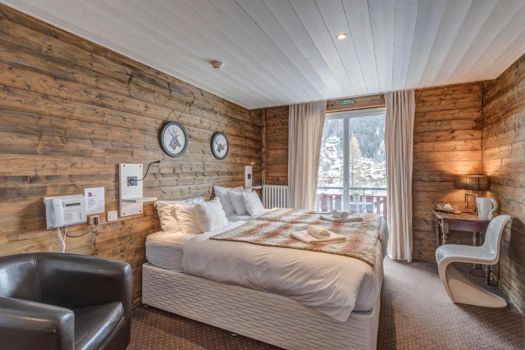 une chambre avec un lit, un bureau et une chaise dans l'établissement Hôtel La Chaumière, à Morzine