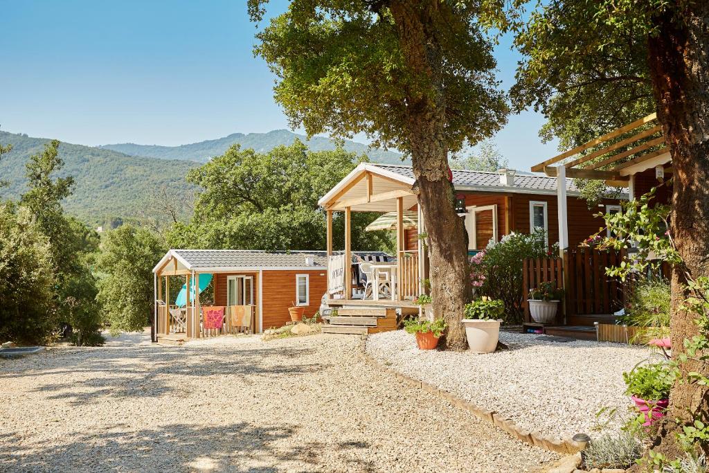 une maison avec une véranda et un arbre dans l'établissement Camping Les Albères - Maeva, à Laroque-des-Albères