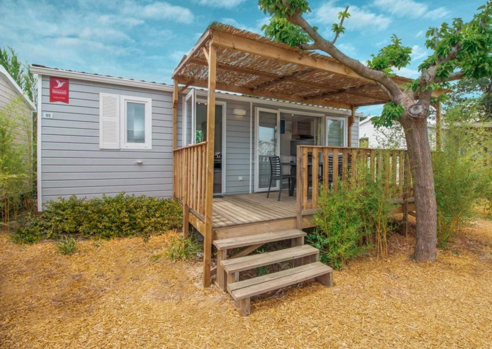 une petite cabine avec une terrasse en bois et un arbre dans l'établissement Camping Ker Yaoulet - Maeva, à Ambon