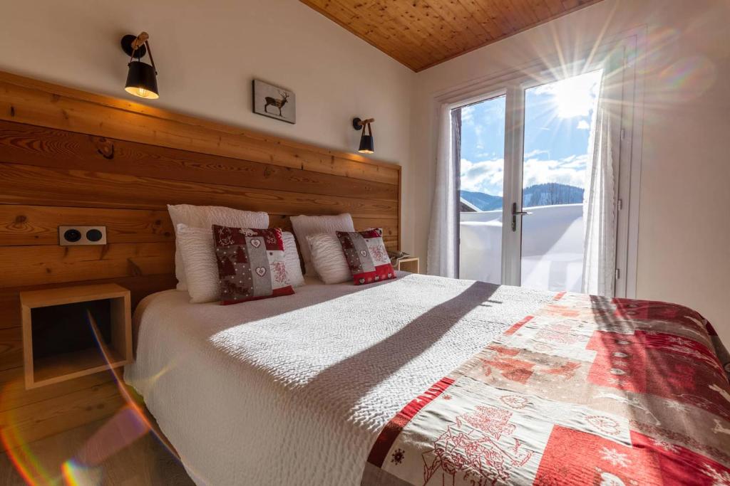 une chambre avec un lit avec une grande fenêtre dans l'établissement Logis Le Vernay, à Autrans