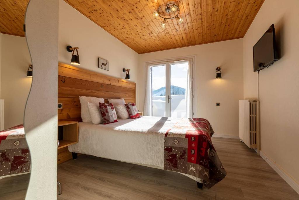 une chambre avec un grand lit et une télévision dans l'établissement Logis Le Vernay, à Autrans