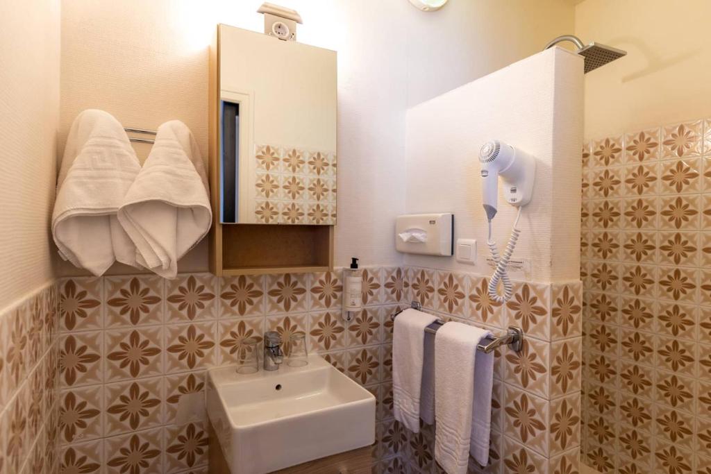 une salle de bain avec un lavabo, un miroir et des serviettes dans l'établissement Logis Le Vernay, à Autrans 37 autres photos