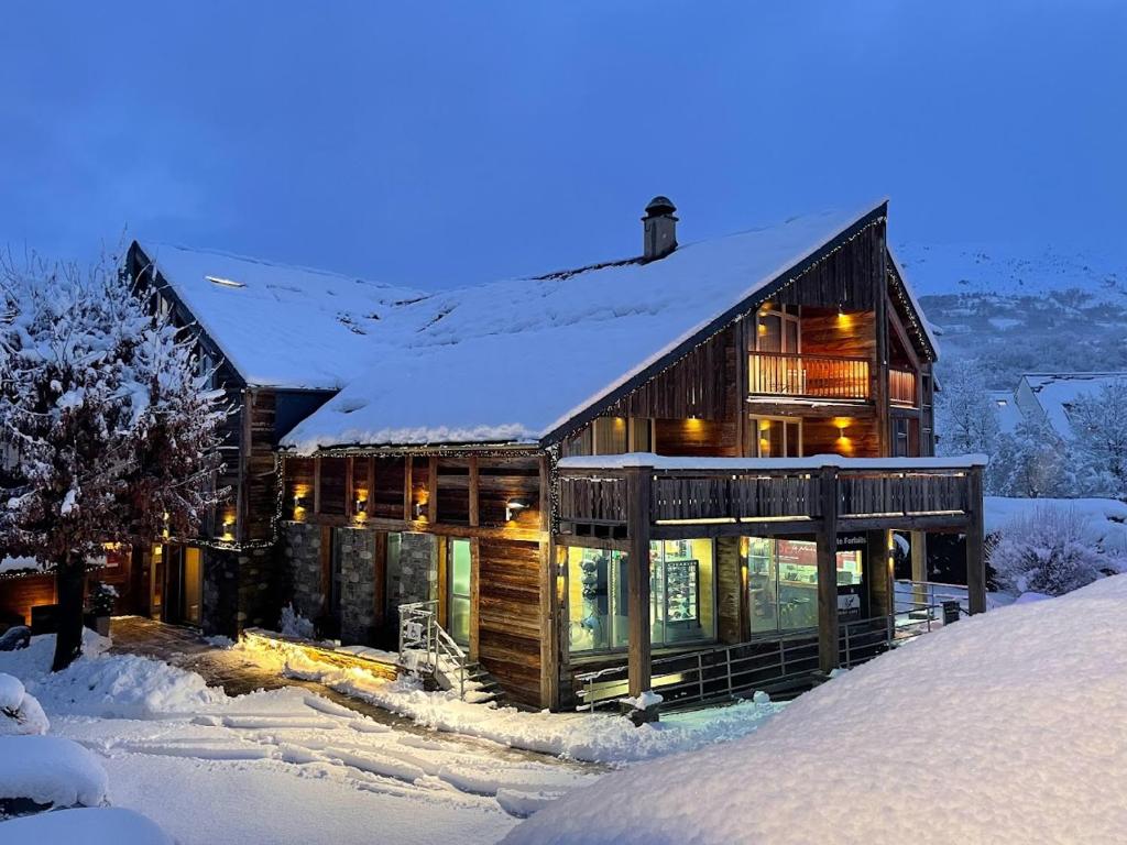 une grande maison en bois avec de la neige sur le toit dans l'établissement Hôtel Neste de Jade, à Saint-Lary-Soulan