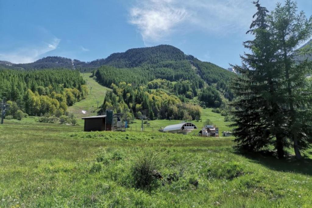un champ avec une grange au milieu d'une montagne dans l'établissement Charming Apartment With Swimming Pool, à La Salle Les Alpes