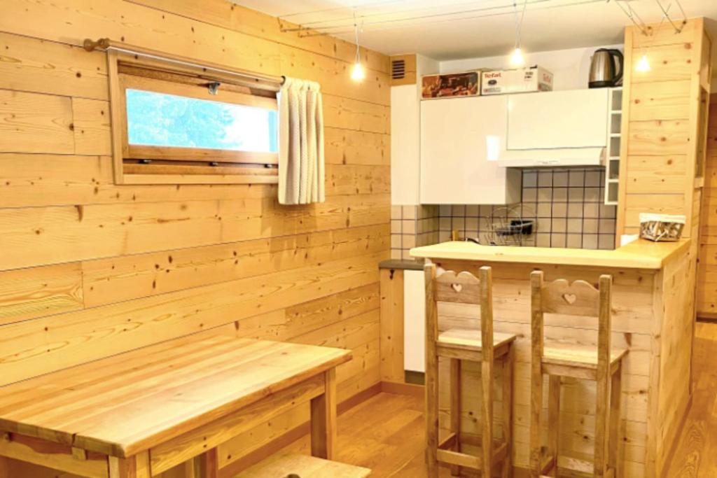 - une cuisine avec des murs en bois, une table et des chaises en bois dans l'établissement Charming Apartment With Swimming Pool, à La Salle Les Alpes