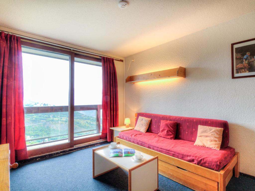 - un salon avec un canapé rouge et une grande fenêtre dans l'établissement Apartment Lunik Orion-29 by Interhome, au Corbier