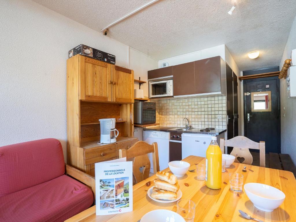 une cuisine avec une table en bois et un canapé rouge dans l'établissement Apartment Vanoise 152 by Interhome, à Val Thorens