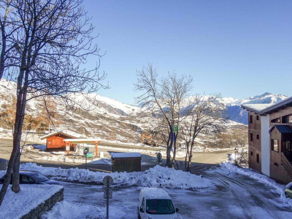 une rue enneigée avec un bâtiment et Une montagne enneigée dans l'établissement Apartment Pegase Phenix-70 by Interhome, au Corbier