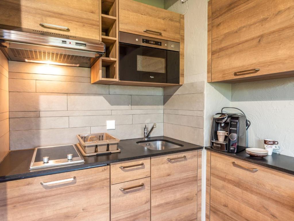 une cuisine avec des armoires en bois et un évier dans l'établissement Studio Les G'rets-10 by Interhome, à Saint-Gervais-les-Bains