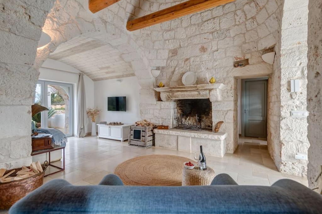 un grand salon avec une grande cheminée en pierre dans l'établissement Trulli Gianpaolo - Luxury Villa, à Ostuni