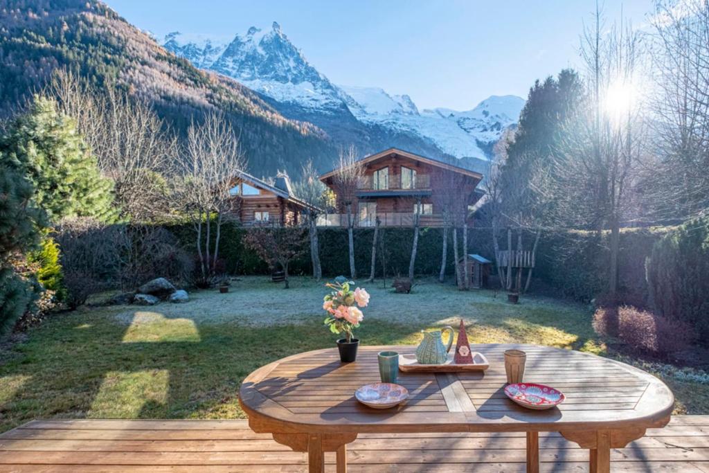 une table en bois sur une terrasse avec une maison en arrière-plan dans l'établissement Nice And Spacious Apt In Chamonix Mont Blanc, à Chamonix-Mont-Blanc