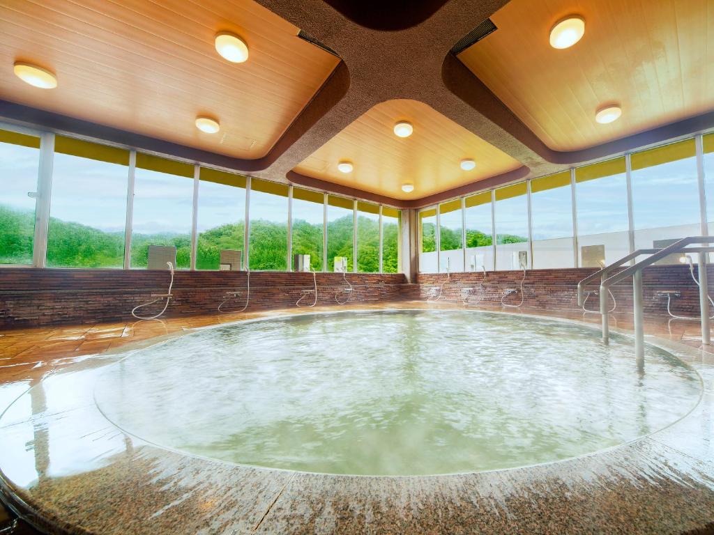 - une grande piscine dans un bâtiment doté de fenêtres dans l'établissement Ooedo Onsen Monogatari Miyoshiya, à Yumura