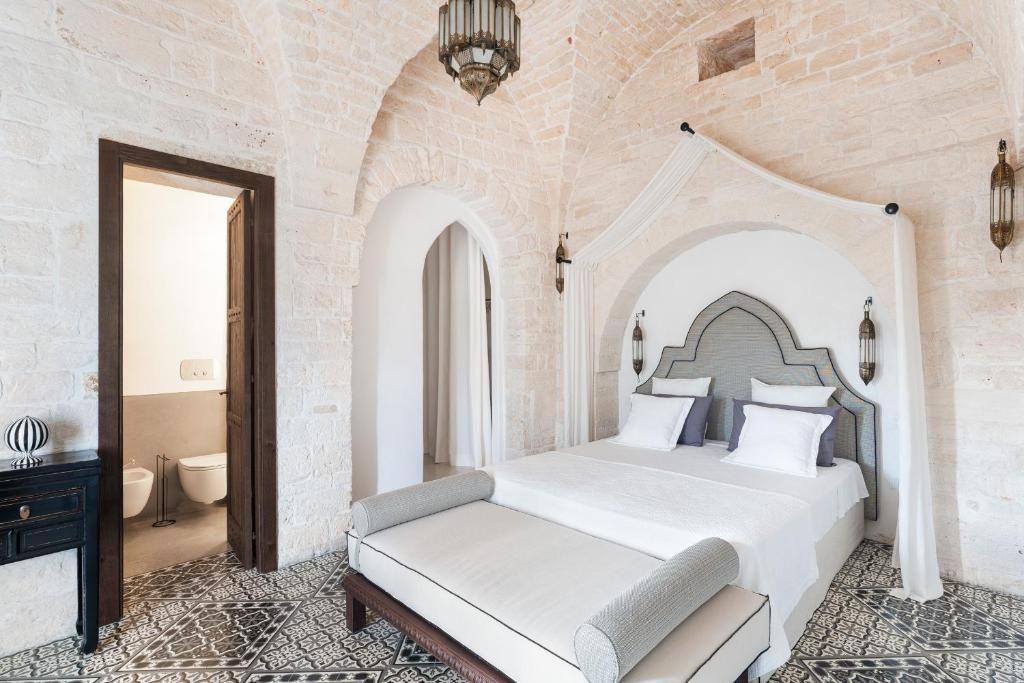 une chambre avec un lit blanc dans une pièce dans l'établissement Trullo Ermes, à Alberobello