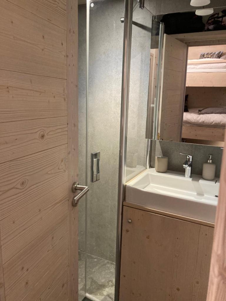 La salle de bains est pourvue d'un lavabo et d'une porte de douche en verre. dans l'établissement Douglas - Appartement au cœur du Jardin Alpin, à Courchevel