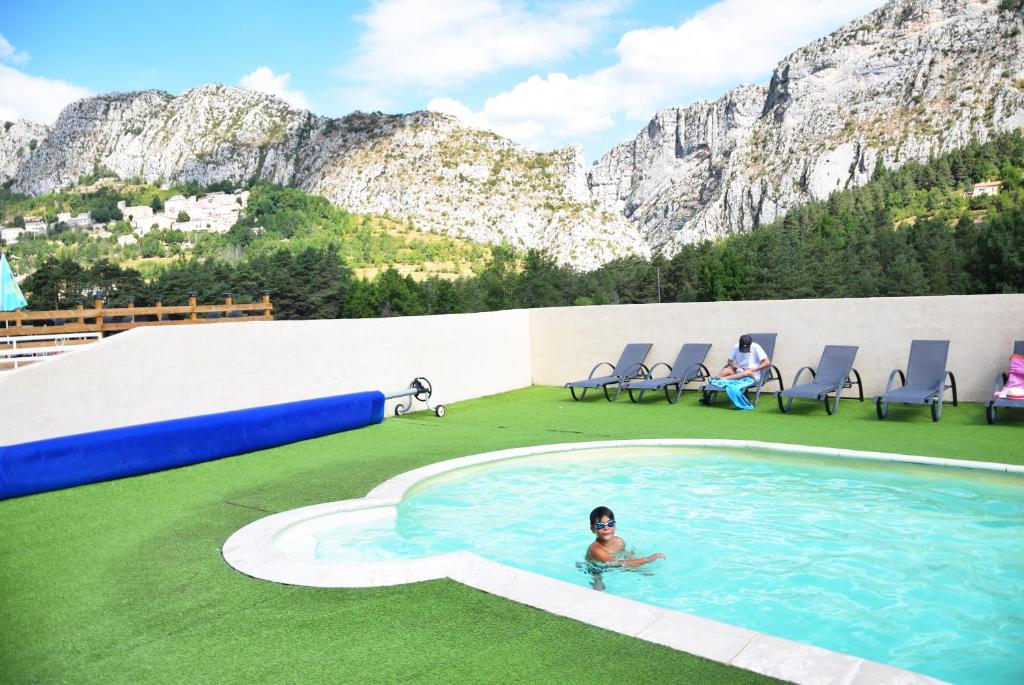 une personne dans une piscine avec des montagnes en arrière-plan dans l'établissement Camping La Pinatelle, à Saint-Auban