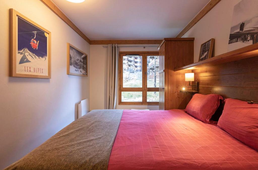 une chambre avec un lit avec une couette rouge et une fenêtre dans l'établissement Arc 1950 Appartement 4 personnes Ski aux pieds, à Arc 1950