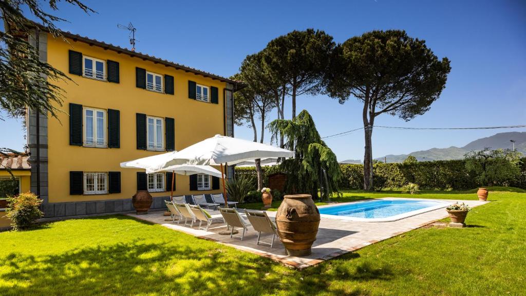 une maison avec une piscine, des chaises et un parasol dans l'établissement VILLA LUIGINA 8, Emma Villas, à Capannori