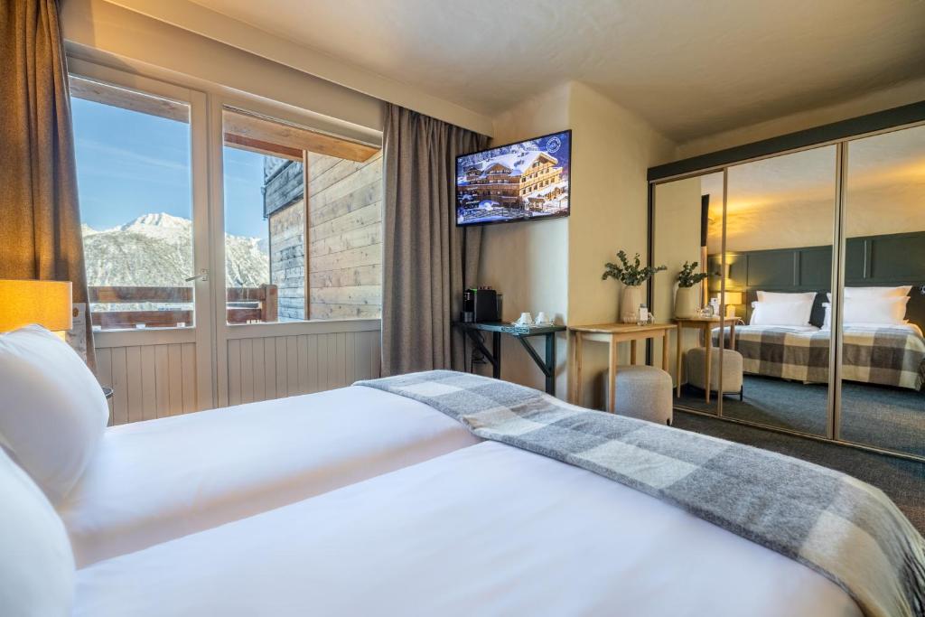 une chambre d'hôtel avec deux lits et une grande fenêtre dans l'établissement Grand Hôtel Courchevel 1850, à Courchevel