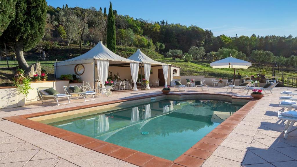 une piscine avec chaises et parasols dans un complexe hôtelier dans l'établissement Villa Beltramonto 14, Emma Villas, à Pomarance