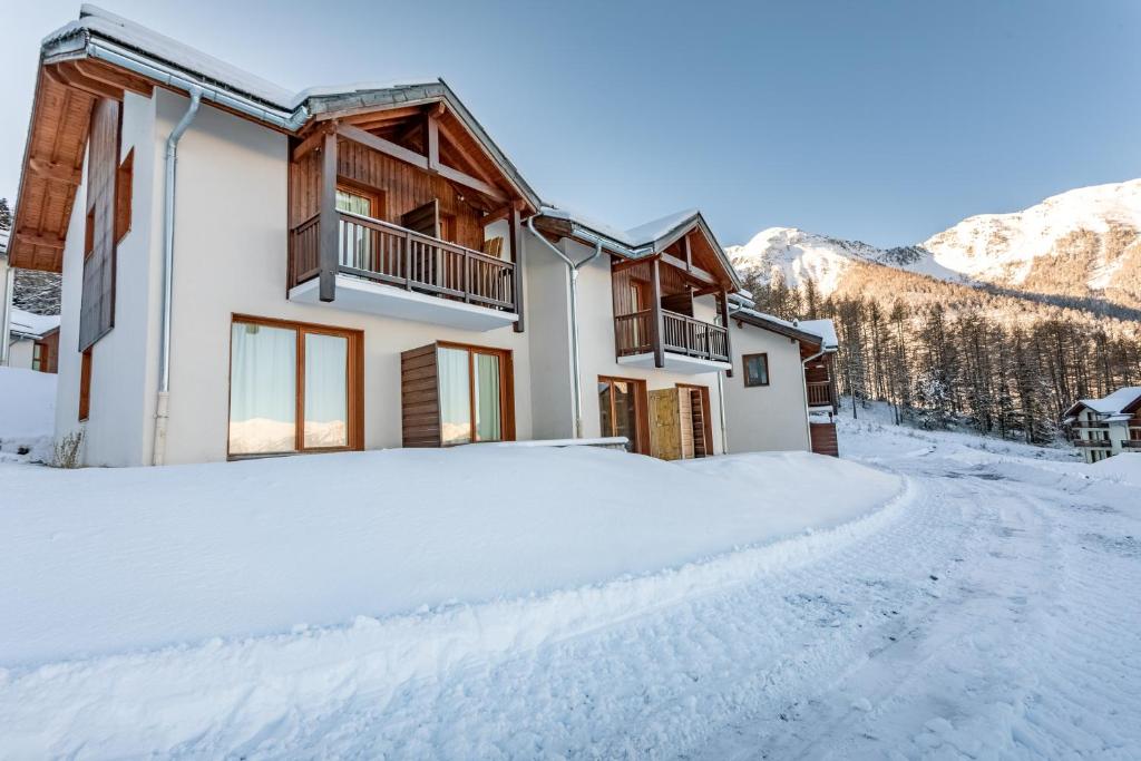 une maison dans la neige dans les montagnes dans l'établissement Le Soleil des Orres - maison pied des pistes - piscine, sauna et hammam, aux Orres
