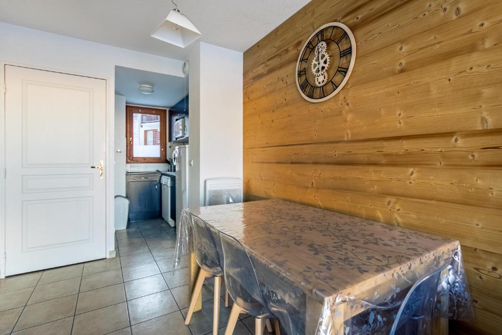 une salle à manger avec une table et une horloge au mur dans l'établissement Le Soleil des Orres - maison pied des pistes - piscine, sauna et hammam, aux Orres 5 autres photos
