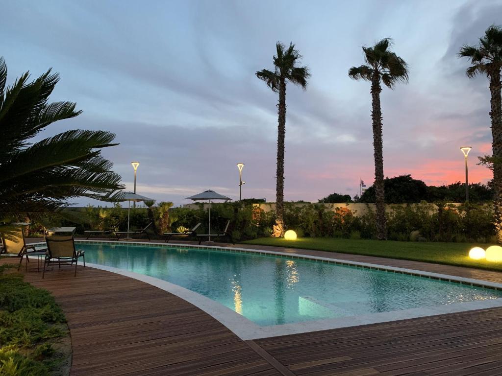 une piscine avec des palmiers et une terrasse en bois dans l'établissement Grand Hotel Torre Fara, à Chiavari