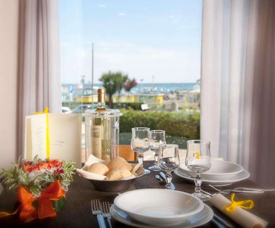 - une table avec des assiettes, des verres et une bouteille de vin dans l'établissement Hotel Caesar, à Rimini