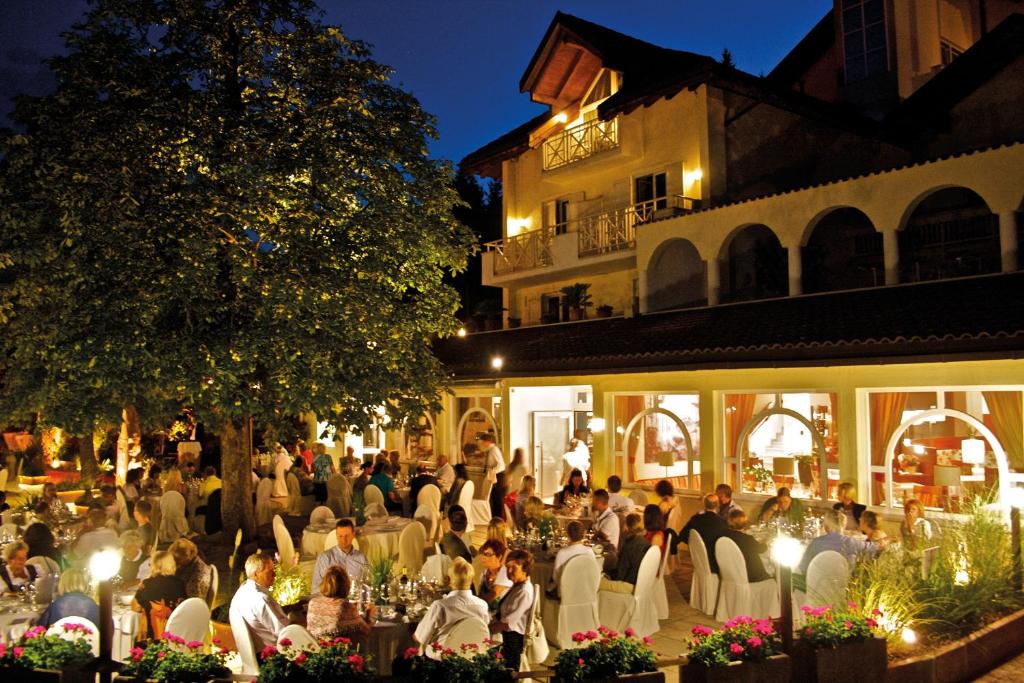 un groupe de personnes assises sous les chaises devant un bâtiment dans l'établissement Seehotel Sparer, à Appiano sulla Strada del Vino 90 autres photos