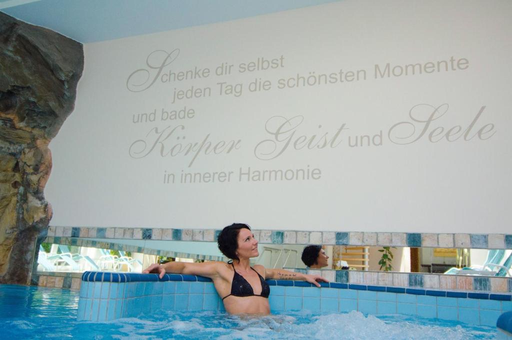 une femme dans une piscine d'un complexe hôtelier dans l'établissement Seehotel Sparer, à Appiano sulla Strada del Vino