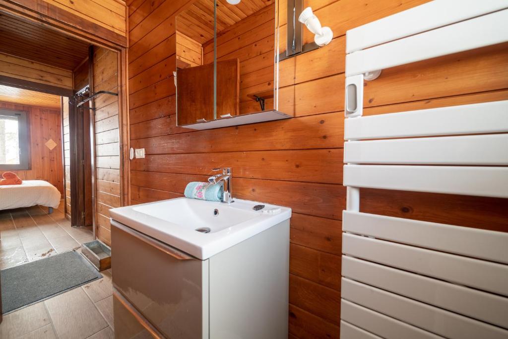 La salle de bains est pourvue d'un lavabo blanc et de murs en bois. dans l'établissement Chalet des Ecureuils - 3 étoiles au pied des pistes, aux Angles