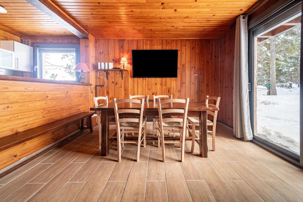 une salle à manger avec une table et des chaises et une télévision dans l'établissement Chalet des Ecureuils - 3 étoiles au pied des pistes, aux Angles