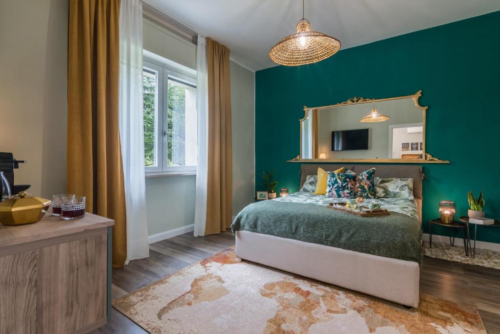 - une chambre avec des murs verts et un lit avec un miroir dans l'établissement Al Quadrato, à Piobbico