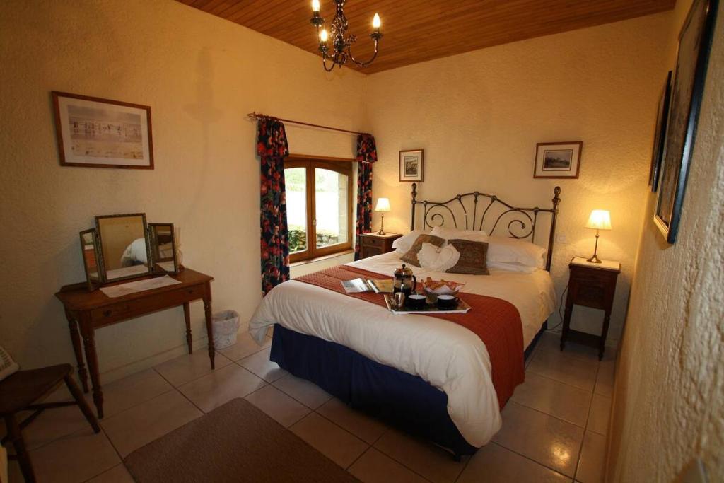 une chambre avec un grand lit et une fenêtre dans l'établissement La Vieille Ferme: superbe complexe de 3 gîtes en pierre avec Piscine au coeur du Périgord Noir, à Saint-Geniès
