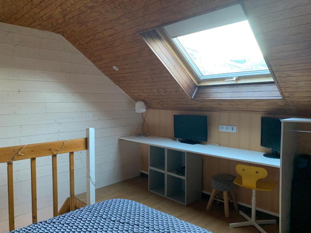 Cette chambre comprend un lit et un bureau avec une fenêtre. dans l'établissement Chalet Élise Plein centre ville, à Gérardmer