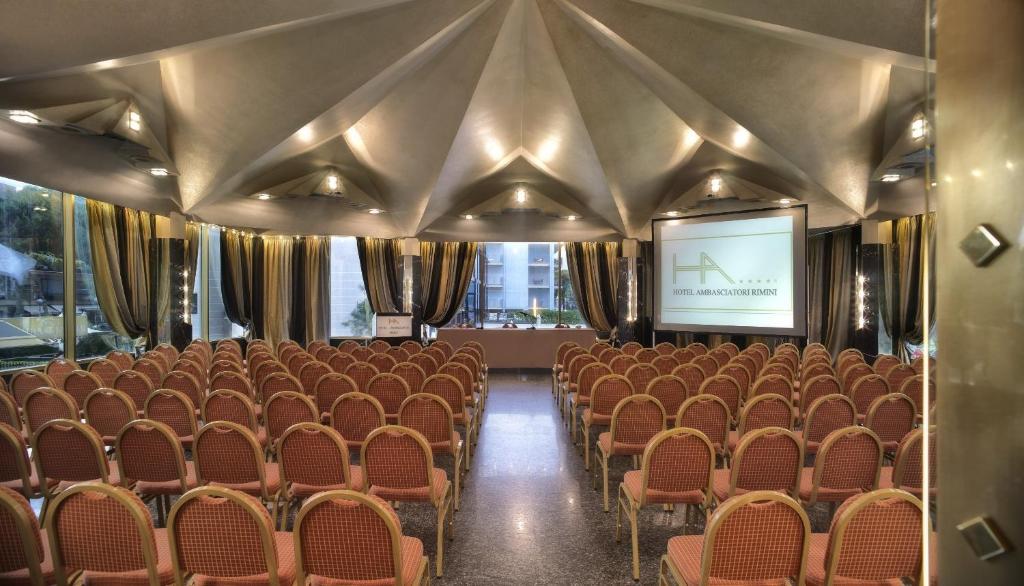 une salle de conférence avec des chaises et un écran dans l'établissement Hotel Ambasciatori, à Rimini 125 autres photos