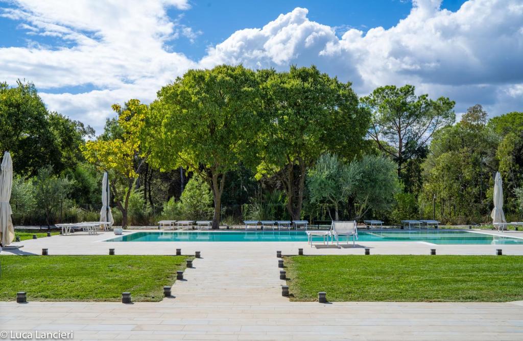 une piscine dans un parc avec des arbres et de l'herbe dans l'établissement Hotel San Vincenzo Resort, à Policoro
